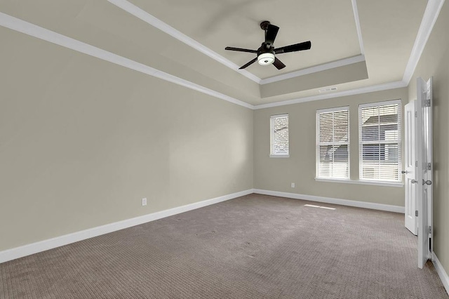 carpeted empty room featuring visible vents, ornamental molding, a tray ceiling, baseboards, and ceiling fan