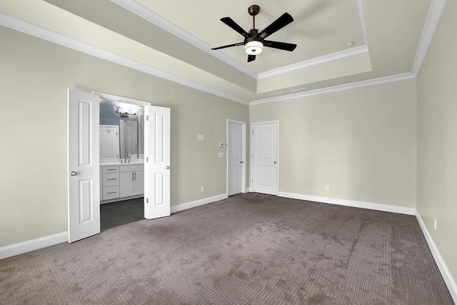 unfurnished bedroom featuring a raised ceiling, baseboards, dark carpet, and ornamental molding