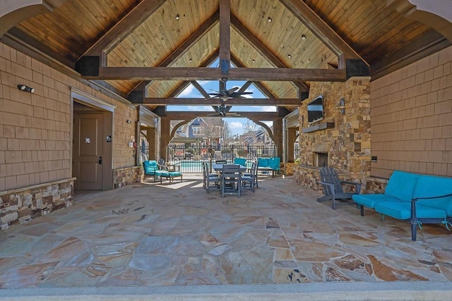 view of patio with a ceiling fan, fence, and an outdoor stone fireplace