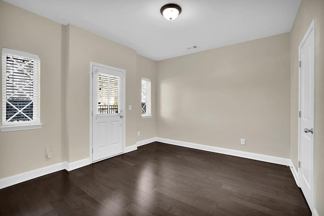 foyer featuring visible vents, baseboards, and dark wood finished floors