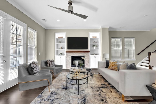 living room featuring visible vents, ornamental molding, ceiling fan, and a glass covered fireplace