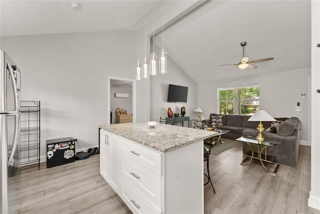 kitchen featuring white cabinets, light hardwood / wood-style flooring, stainless steel fridge, decorative light fixtures, and light stone counters