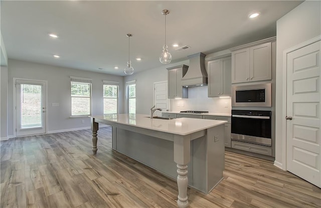 2516 Cadenza Cir, Dacula, GA 30019 - kitchen with stainless steel appliances, custom range hood, gray cabinetry, light countertops, and a kitchen island with sink
