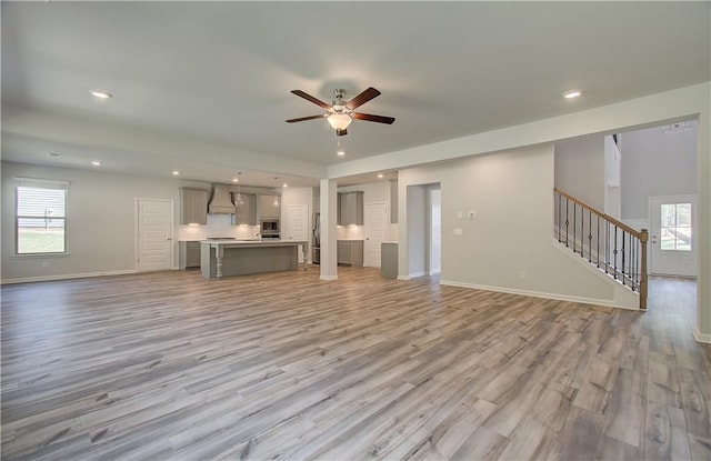 2516 Cadenza Cir, Dacula, GA 30019 - unfurnished living room with a ceiling fan, stairs, light wood-style floors, healthy amount of natural light, and recessed lighting