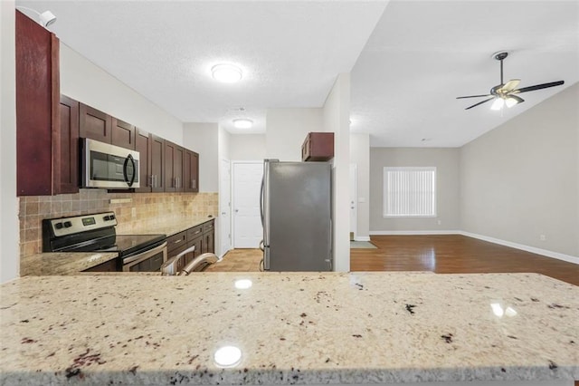 5600 Walnut Creek Ct NW, Lilburn, GA 30047 - kitchen with stainless steel appliances, decorative backsplash, baseboards, wood finished floors, and light stone countertops
