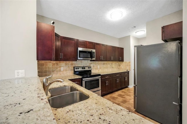 5600 Walnut Creek Ct NW, Lilburn, GA 30047 - kitchen featuring appliances with stainless steel finishes, a sink, tasteful backsplash, light stone countertops, and a textured ceiling