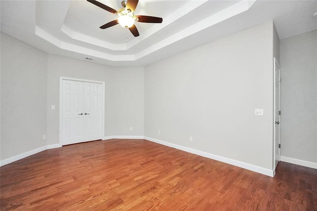 5600 Walnut Creek Ct NW, Lilburn, GA 30047 - unfurnished bedroom with a tray ceiling, wood finished floors, baseboards, a closet, and a ceiling fan