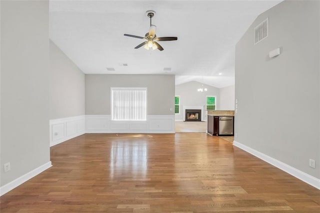 5600 Walnut Creek Ct NW, Lilburn, GA 30047 - unfurnished living room featuring ceiling fan, vaulted ceiling, wood finished floors, a warm lit fireplace, and wainscoting