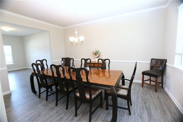 dining room with dark wood-type flooring, ornamental molding, and a notable chandelier