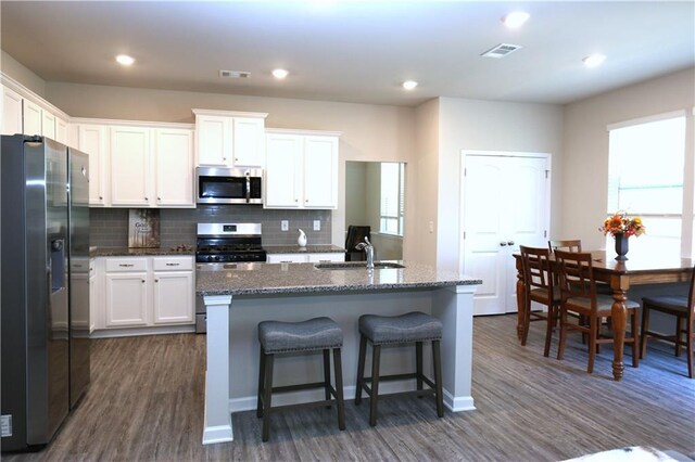 kitchen featuring sink, white cabinets, appliances with stainless steel finishes, and a center island with sink