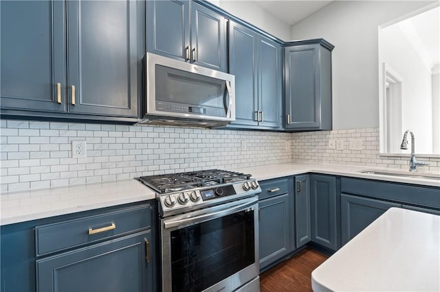 kitchen with dark hardwood / wood-style flooring, stainless steel appliances, sink, blue cabinetry, and a center island