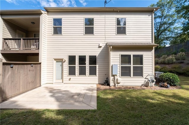 rear view of house featuring a balcony, a patio area, and a lawn