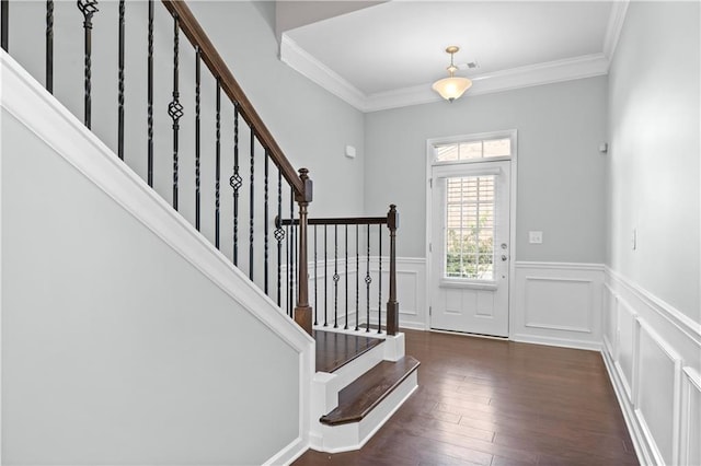 foyer entrance with ornamental molding and dark wood-type flooring