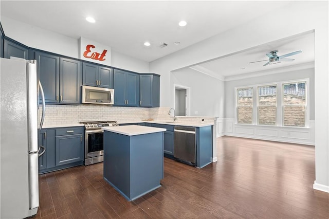 kitchen featuring dark wood-type flooring, crown molding, a kitchen island, kitchen peninsula, and stainless steel appliances