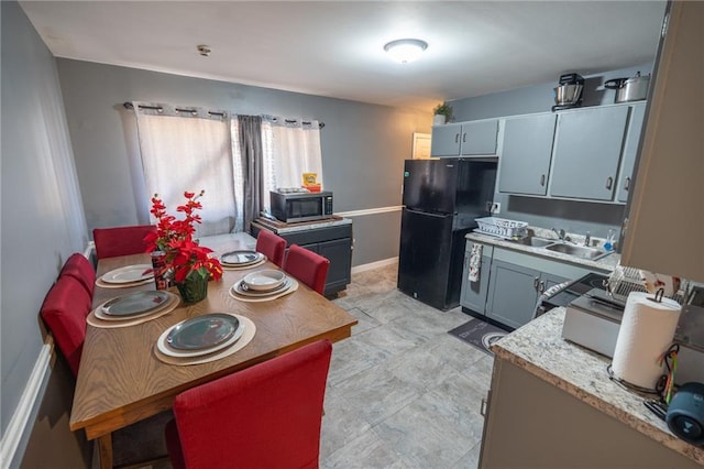 kitchen with sink, black refrigerator, and gray cabinetry