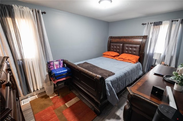 bedroom with dark hardwood / wood-style floors and multiple windows