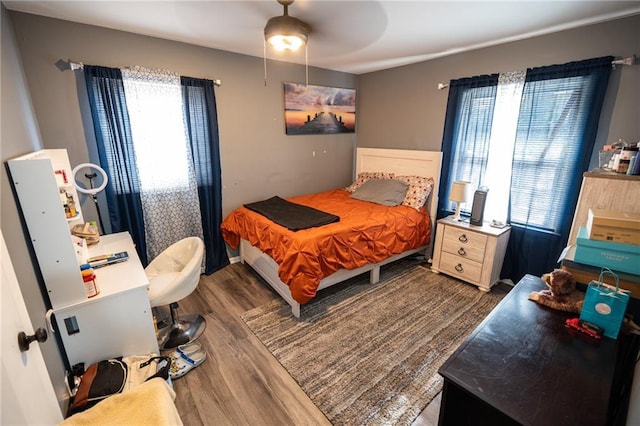 bedroom with ceiling fan, dark hardwood / wood-style flooring, and multiple windows