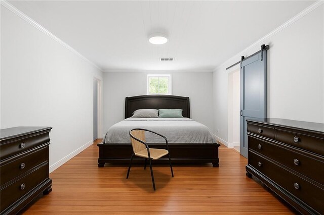 5150 Wheat St NE, Covington, GA 30014 - bedroom with light wood-style flooring, ornamental molding, a barn door, and baseboards