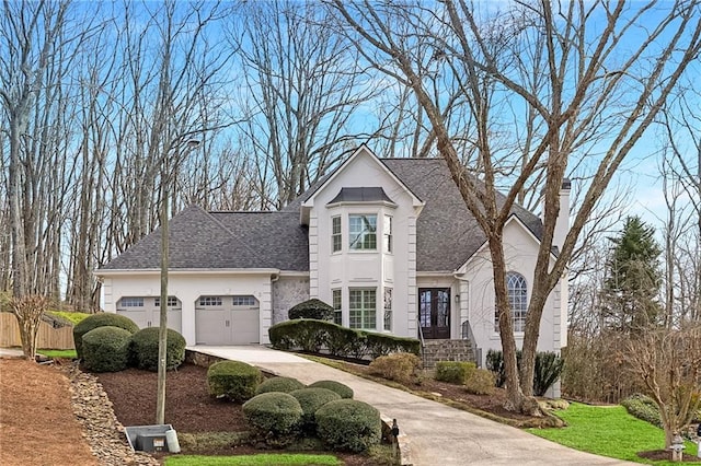 french country inspired facade featuring stucco siding, concrete driveway, a garage, and a shingled roof