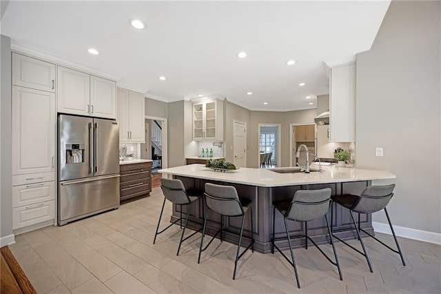 kitchen with high end refrigerator, a peninsula, a kitchen breakfast bar, and a sink