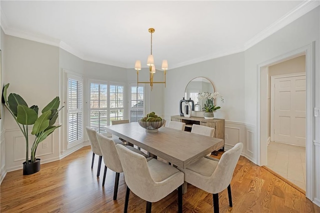 dining area with crown molding, a decorative wall, light wood-style floors, and a wealth of natural light