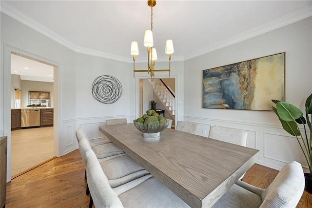 dining space featuring stairs, a chandelier, ornamental molding, and light wood finished floors