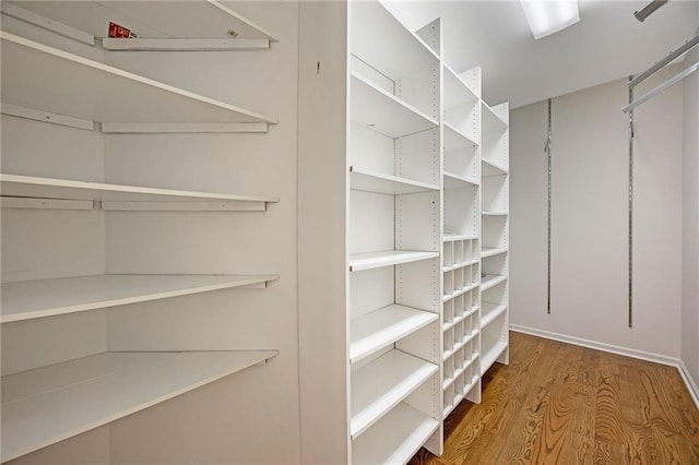 walk in closet with wood finished floors