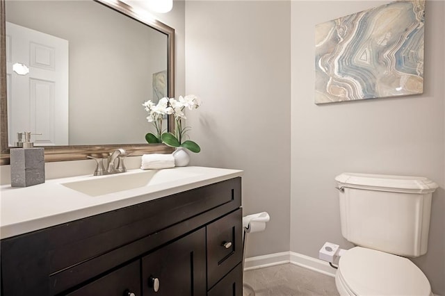 half bathroom with baseboards, toilet, and vanity