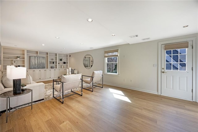 living room with visible vents, built in shelves, baseboards, light wood-type flooring, and recessed lighting