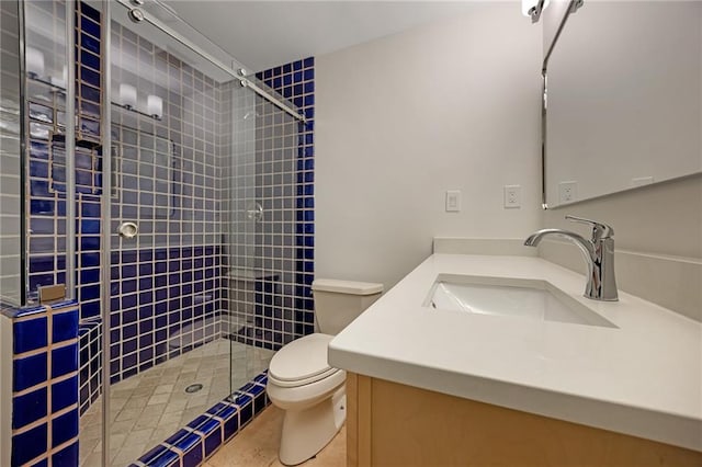 bathroom with a tile shower, toilet, and vanity