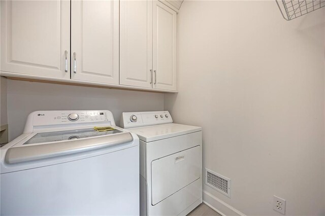 clothes washing area featuring washer and clothes dryer, visible vents, and cabinet space