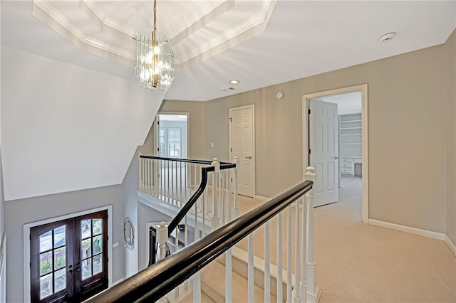 hall with baseboards, a tray ceiling, carpet floors, an upstairs landing, and french doors