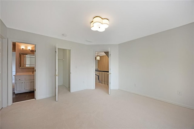 unfurnished bedroom with a walk in closet, baseboards, a closet, and carpet floors