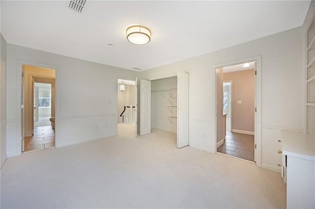 unfurnished bedroom with light carpet, visible vents, and a closet