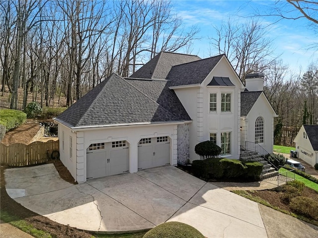 view of front of house with roof with shingles, concrete driveway, an attached garage, and fence