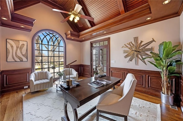 home office featuring a wainscoted wall, beamed ceiling, ornamental molding, wood finished floors, and wood ceiling