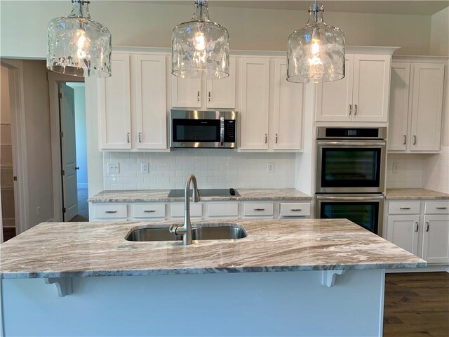 kitchen featuring white cabinets, a center island with sink, and appliances with stainless steel finishes