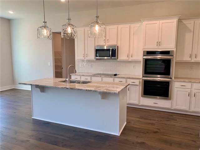 kitchen featuring dark wood-type flooring, sink, an island with sink, white cabinets, and appliances with stainless steel finishes