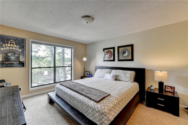 bedroom with light carpet, a textured ceiling, and baseboards