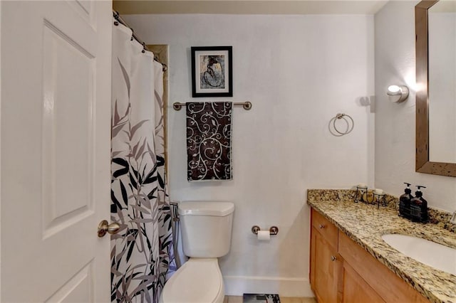 bathroom featuring toilet, vanity, and baseboards