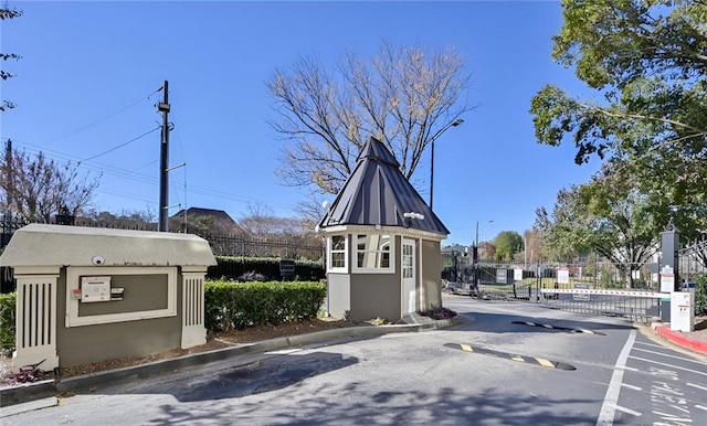 view of road with a gate, curbs, a gated entry, and street lights