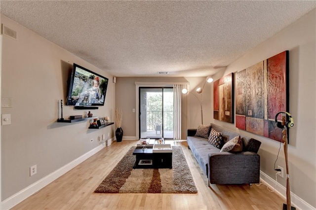 living room featuring a textured ceiling, wood finished floors, visible vents, and baseboards