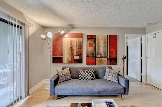 living area with plenty of natural light, a textured ceiling, baseboards, and wood finished floors