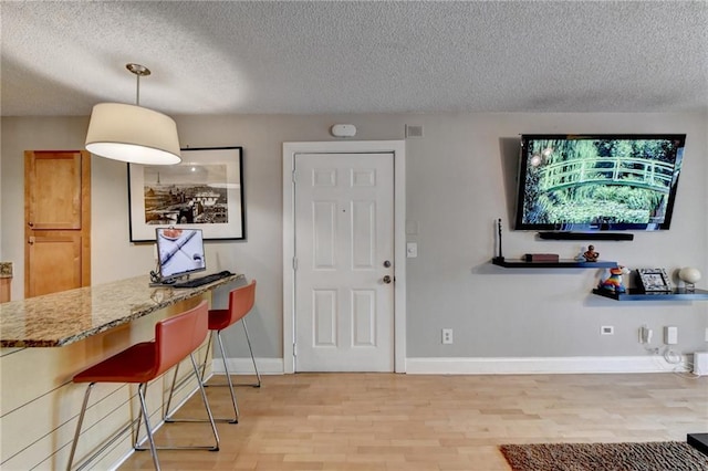 foyer with a textured ceiling, light wood-type flooring, visible vents, and baseboards