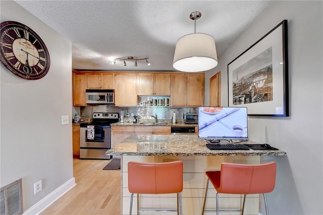 kitchen featuring tasteful backsplash, visible vents, a peninsula, stainless steel appliances, and a textured ceiling