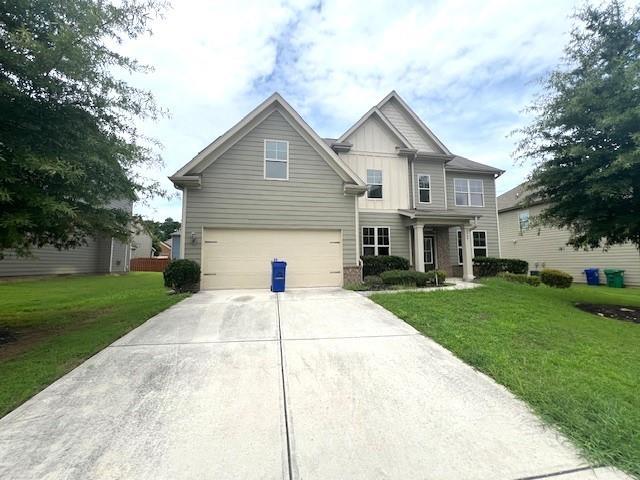 2469 Osceola Rd, Lithonia, GA 30058 - view of front facade featuring board and batten siding, concrete driveway, an attached garage, and a front lawn