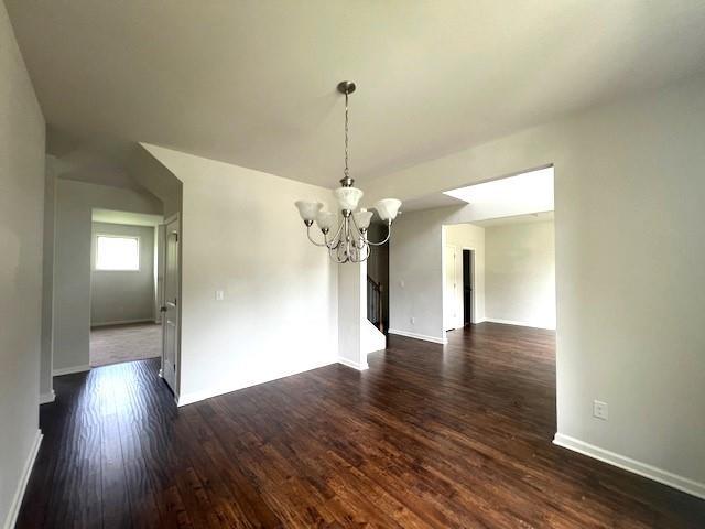 2469 Osceola Rd, Lithonia, GA 30058 - unfurnished dining area featuring a chandelier, dark wood-type flooring, and baseboards