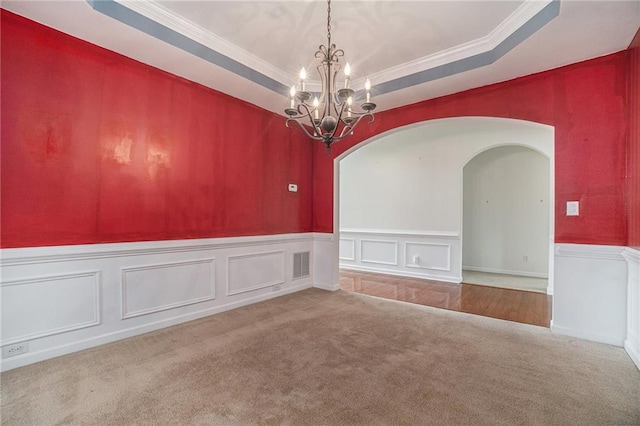 7761 Parkside Dr, Lithia Springs, GA 30122 - carpeted empty room with a chandelier, arched walkways, crown molding, wainscoting, and a raised ceiling