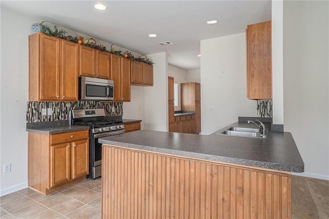7761 Parkside Dr, Lithia Springs, GA 30122 - kitchen with stainless steel appliances, a peninsula, dark countertops, a sink, and decorative backsplash