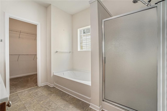 7761 Parkside Dr, Lithia Springs, GA 30122 - full bathroom featuring a shower stall, a garden tub, a spacious closet, and baseboards